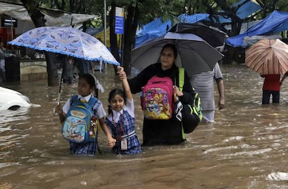 Dos alumnos acompañados tratan de ir a la escuela en Mumbai, India.
