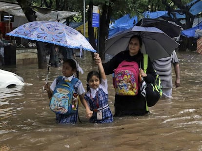 Dos alumnos acompa&ntilde;ados tratan de ir a la escuela en Mumbai, India.