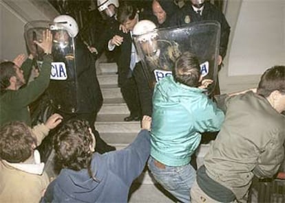 Policías antidisturbios protegen a Alberto Fernández ante un grupo de jóvenes que intenta agredirle.