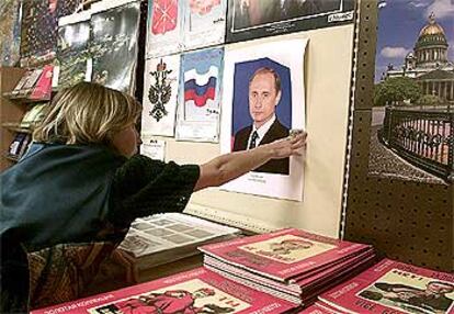 Una mujer cuelga una foto de Putin en la tienda en la que trabaja, ayer en San Petersburgo.
