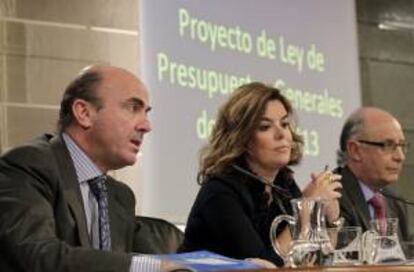 El ministro de Economía, Luis de Guindos (izda), junto a la vicepresidenta del Gobierno, Soraya Sáenz de Santamaría, y el titular de Hacienda y Administraciones Públicas, Cristóbal Montoro, durante la rueda de prensa que ofrecieron ayer al término de la reunión del Consejo de Ministros en la que se aprobó el proyecto de Presupuestos Generales del Estado para 2013.