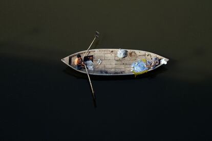 Plano cenital de un pescador indio en una barca en el río Ganges, santo para los hindúes, en Allahabad, India.