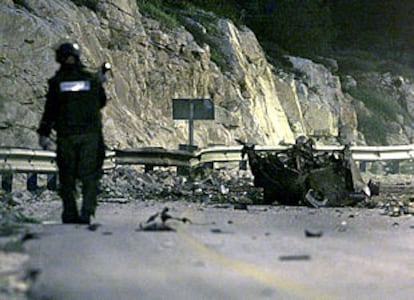 Un agente de policía israelí examina los restos del coche bomba que hizo explosión cerca de Jerusalén.