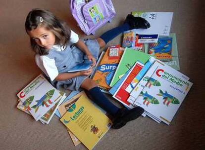 Alicia Cuéllar, de seis años, espera al comienzo del colegio rodeada de sus nuevos libros.