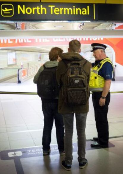 Un policía habla con dos viajeros después de que la terminal norte del aeropuerto de londinense de Gatwick se cerrara por un paquete sospechoso.