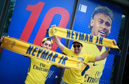 Seguidores del PSG posan con bufandas en el exterior de la tienda del club en los Campos Elíseos en París.