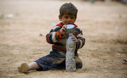 A displaced Syrian child, who fled the countryside surrounding the Islamic State (IS) group stronghold of Raqa, plays with a tin can and a plastic bottle on at a temporary camp in the village of Ain Issa on April 28, 2017. / AFP PHOTO / DELIL SOULEIMAN