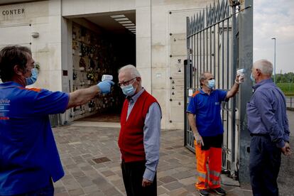 Dos parientes de fallecidos por covid-19 entran en el cementerio de Brescia, localidad vecina de Bérgamo y también enormemente golpeada por la pandemia, mientras son sometidos a un control de temperatura para poder participar en uno de los funerales exprés.