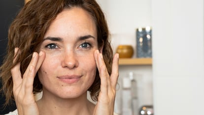 Mujer colocándose crema en la cara.