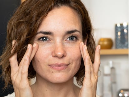 Mujer colocándose crema en la cara.