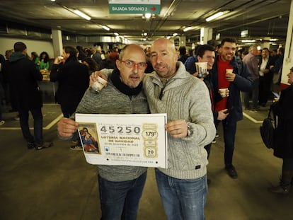 Raúl y Luis (derecha), de la empresa Tragsatec, celebran el tercer premio de la Lotería de Navidad en la sede de la empresa en Madrid.