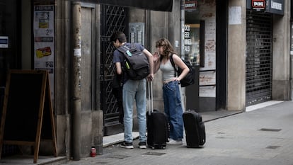 Dos turistas frente a un portal a punto de entrar en un piso turistico en la Calle Aragó de Barcelona.