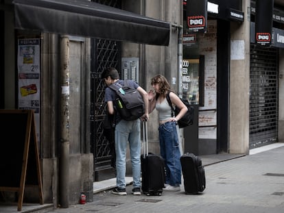 Turistas con maletas ante un edificio de Barcelona con pisos turísticos, en junio.