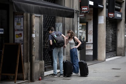 Dos turistas frente a un portal a punto de entrar en un piso turistico en la Calle Aragó de Barcelona.