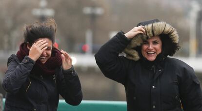 Dos mujeres se protegen contra el viento y la lluvia en el puente del Kursaal de San Sebastián.