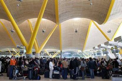 Decenas de pasajeros esperan ante los mostradores de facturación en la nueva terminal de Barajas.
