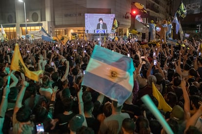 Seguidores de Javier Milei le miran dar su discurso de victoria desde afuera de la sede de campaña, el 19 de noviembre.