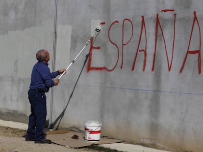 Una persona cubre una pintada contra España.