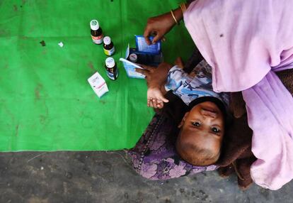 Una mujer musulmana rohingya cuida de su hijo mientras espera seguir el camino hasta el campo de refugiados en Banglads.