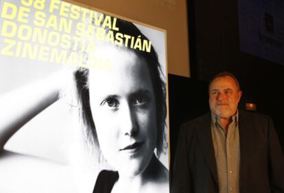 El director del Festival, Mikel Olaciregui, posa junto al cartel de la Sección Oficial, firmado por Óscar Mariné.