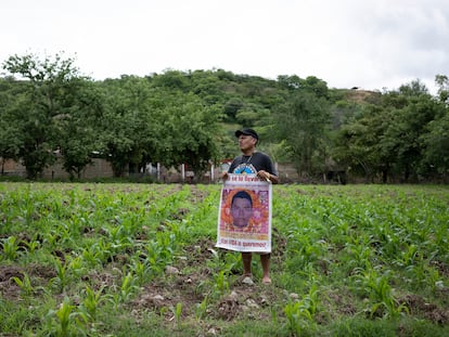 Clemente Rodríguez, padre de Christian, uno de los 43 normalistas, en su milpa con un cartel con la imagen de su hijo.