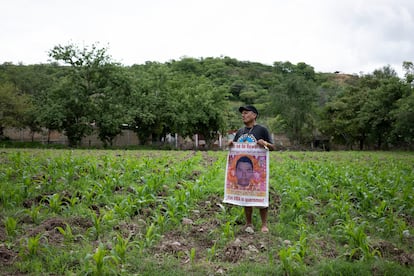 Clemente Rodríguez, padre de Christian, uno de los 43 normalistas, en su milpa con un cartel con la imagen de su hijo.