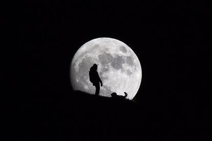 Una persona pasea junto a su perro a la luz de la luna en Croix des Chaux (Suiza).