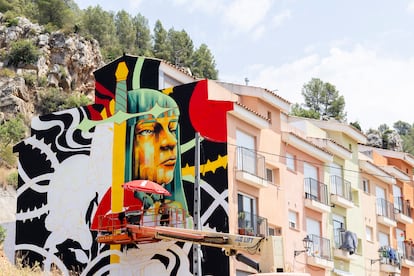 El muralista Santa Gross pinta una fachada en Fanzara, en Castellón, durante el festival de arte urbano MIAU.
