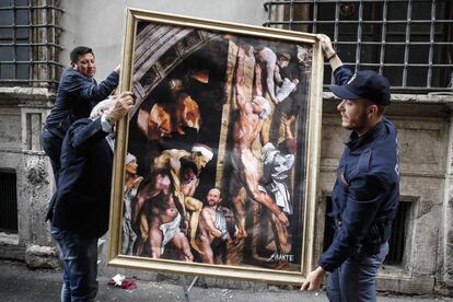 Dos policías retiran la obra del artista urbano 'El incendio del Nazareno', que parodia una pieza de Sanzio con Berlusconi y Renzi. 