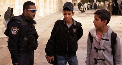 Un policía israelí, con dos niños árabes en Jerusalén.