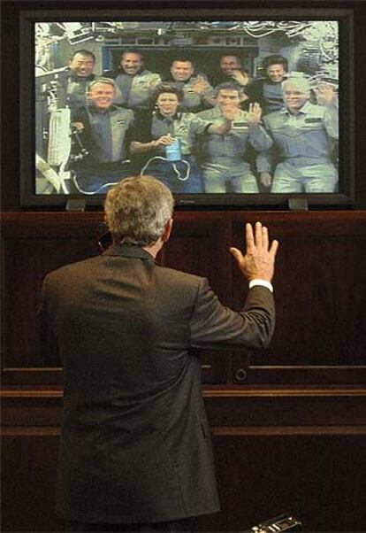 El presidente Bush saluda a los astronautas tras conversar con ellos.