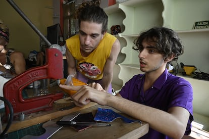 Gus Bianchi, fundadora e integrante del taller, ayuda a una compañera en el manejo de la maquina para perforar el cuero.