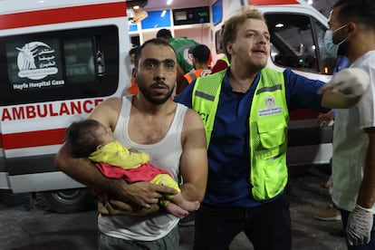 Un hombre transporta a un bebé herido a un hospital en Gaza, tras un ataque israelí, este miércoles. 