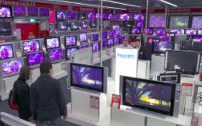 Clientes en una tienda Media Markt miran televisores.