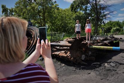 Una madre fotografía a sus hijos en los restos de un tanque en el pueblo de Lukianivka, en la región de Kiev