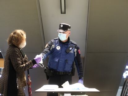 Un policía municipal reparte mascarillas en el acceso al intercambiador de Avenida de América.