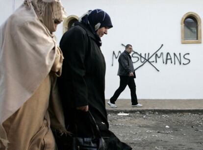 Dos musulmanas pasan ante una mezquita con una pintada insultante en Saint-Etienne (Francia).