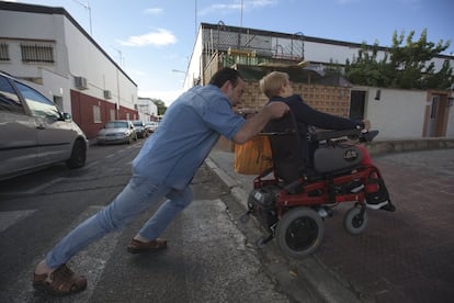 Francisco Javier Jiménez, vecino de Entrevías, ayuda a Maite a subir la acera que da acceso a su casa. Pese al motor eléctrico, Jiménez tiene que empujar los 45 kilos de la silla. La operación se repite cada vez que Corbacho sale a la calle. En ocasiones tiene que esperar a que pase alguien o llamar por teléfono a algún vecino para que la ayude.