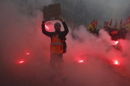 Un ferroviario francés sostiene un cartel entre bengalas durante una manifestación en París.