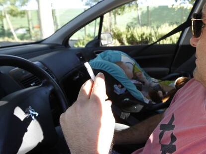 Un conductor fuma en el interior de un vehículo junto a un bebé.