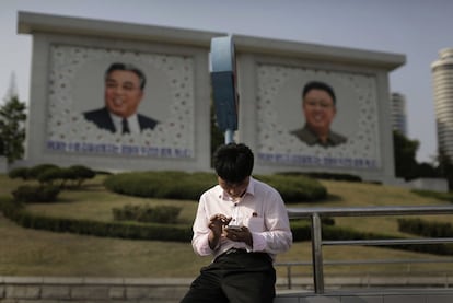 Hace una década, solo un pequeño grupo de funcionarios militares y del régimen selecto tenía acceso a teléfonos inteligentes. Ahora, de acuerdo con los informes financieros más recientes del proveedor principal, se estima que hay entre 2,5 y 3 millones de teléfonos móviles en Corea del Norte, un país de 25 millones. En la foto, un hombre utiliza un teléfono inteligente frente a los retratos de los fallecidos líderes norcoreanos Kim Il Sung (i) y Kim Jong Il (d), el 5 de mayo de 2015, en Pyongyang.