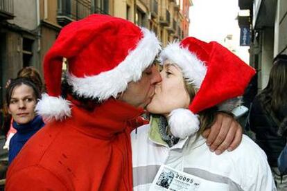 Una pareja de Vic agraciada con el premio <i>gordo</i> se besa mientras exhibe el número premiado.