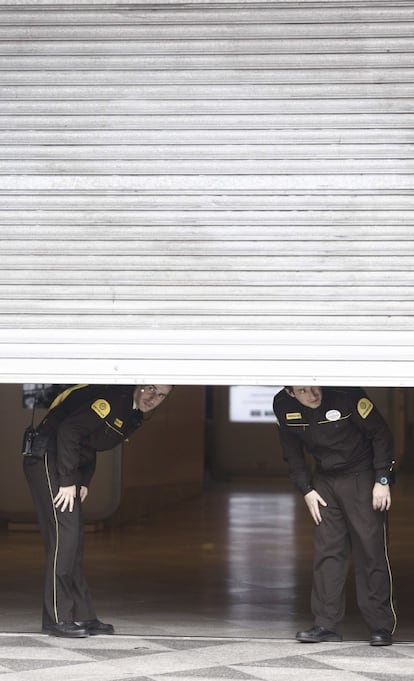 Agentes de seguridad privada miran hacia la calle desde el interior de una empresa, en el centro comercial Triangle de plaza Catalunya, en Barcelona.