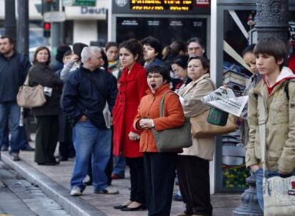 Un grupo de gente esperaba resignadamente en una parada la llegada del autobús, en la mañana de ayer, en Valencia.