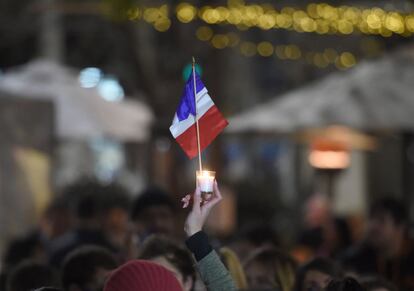 Un miembro de la comunidad francesa de Sidney alza la mano sujetando una vela con la bandera de Francia.