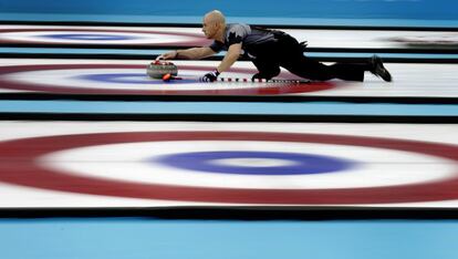 La canadiense Ryan Fry ofrece la roca durante el partido de Curling masculino por la medalla de oro contra Gran Bretaña.