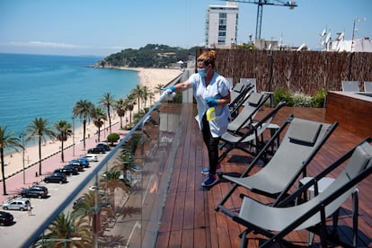 Una empleada limpia tumbonas en una terraza de un hotel en Lloret de Mar.