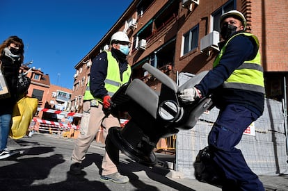 Dos operarios retiran los enseres durante el desalojo de las cuatro viviendas de la calle Presa en San Fernando de Henares (Madrid).