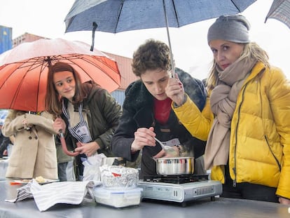 Una familiar de un concursante protege a este e la lluvia con un paraguas en la última prueba presencial para 'MasterChef' 6 en Getafe.