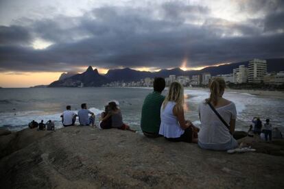 Algunos turistas veen la puesta del sol en el Arpoador, en Río.